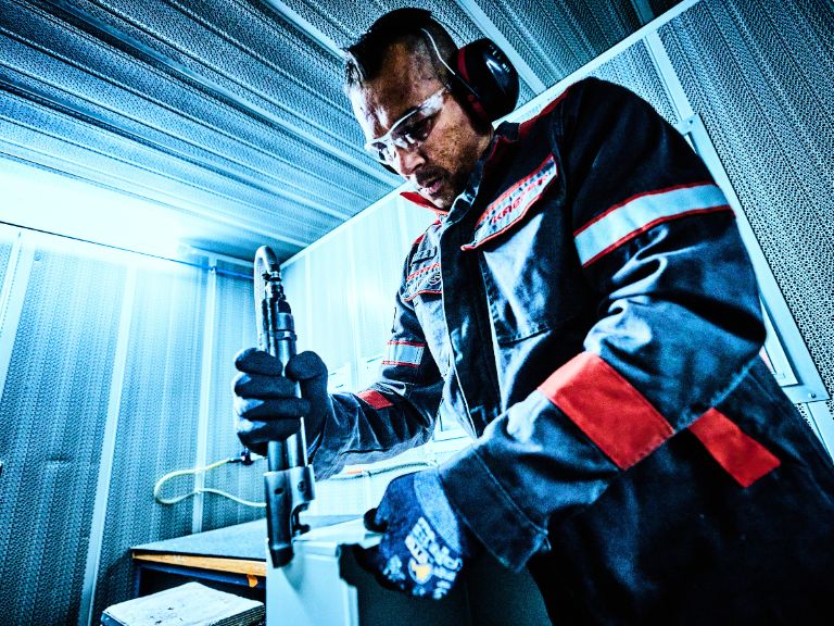 KAEFER operative in the workshop working with sheet metal